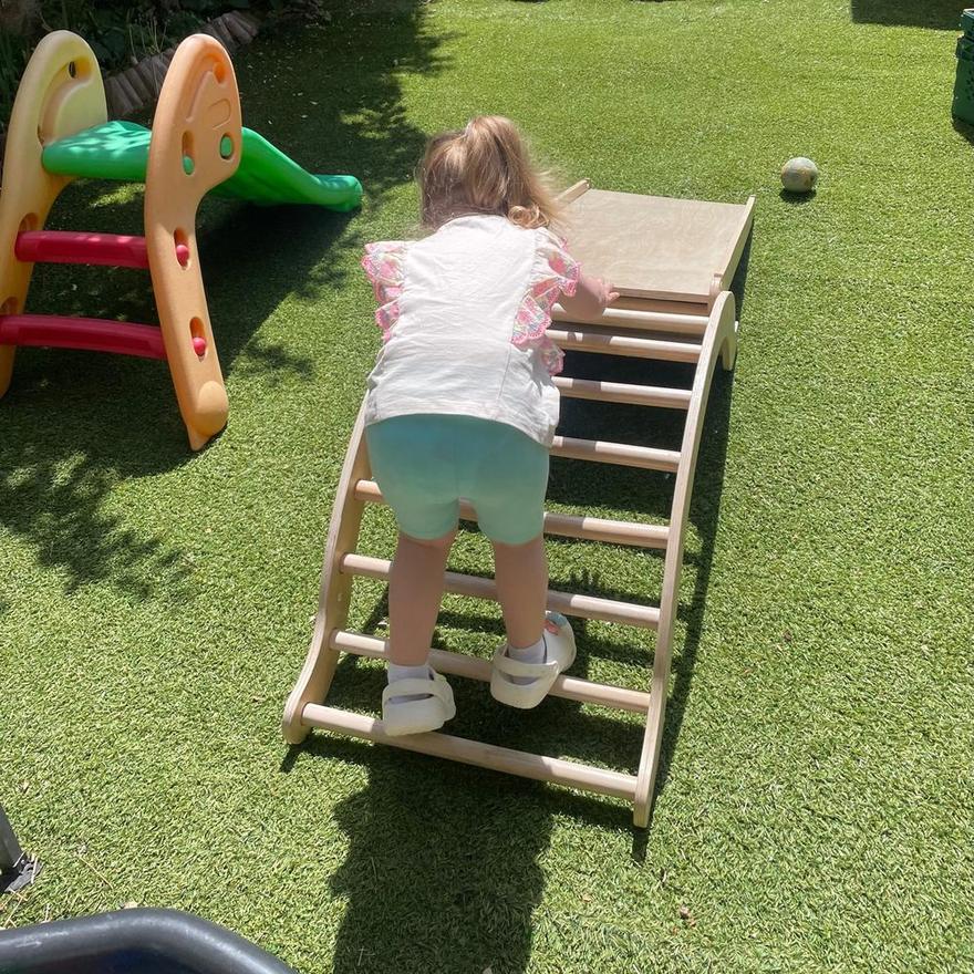 A child climbing a wooden frame in the garden
