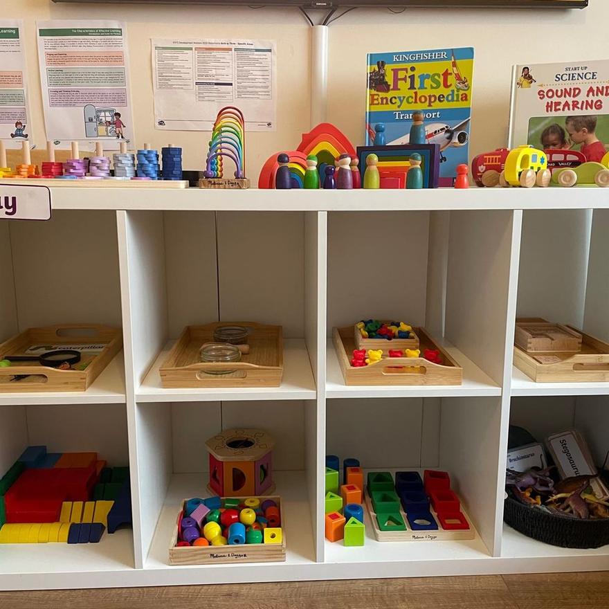 Low open shelves holding trays of Montessori activities