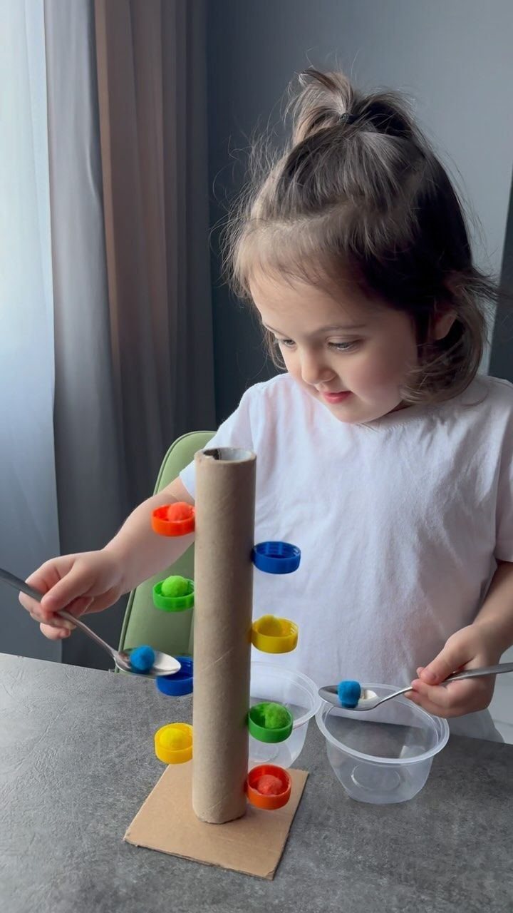 A toddler posting balls into a tube