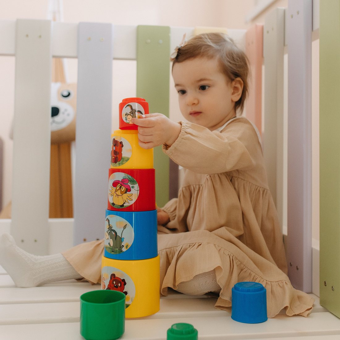 A toddler carefully placing the top cup on a tower of stacking cups